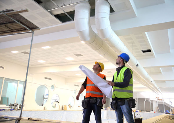 Bauarbeiter sehen sich Baupläne in einer Industriehalle an